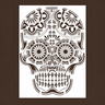 Valkoinen A4-kokoinen Sugar Skull -sabluuna, jossa koristeellinen pääkallo, kukkamaiset silmät, symmetriset ornamentit ja yksityiskohtainen hammaskuvio.