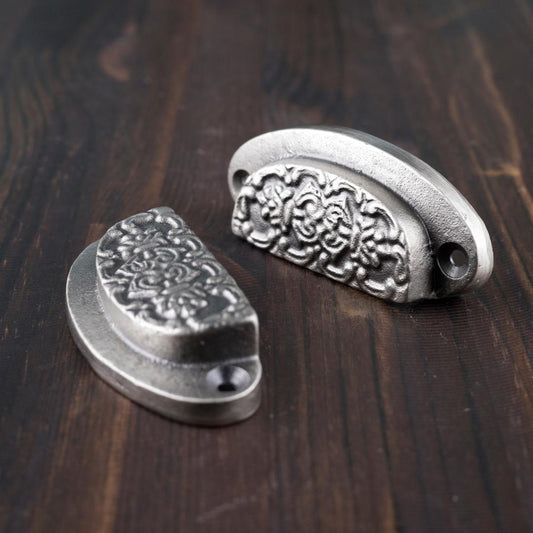 Kuviollinen kuppivedin esim. laatikkoon. Kiinnitysruuvit sis. tuotteeseen.  Myydään yksittäin.  Väri: antiikkihopea  Koko: leveys 78 mm, korkeus 32 mm, syvyys 18 mm.  Ruuviväli: 65 mm